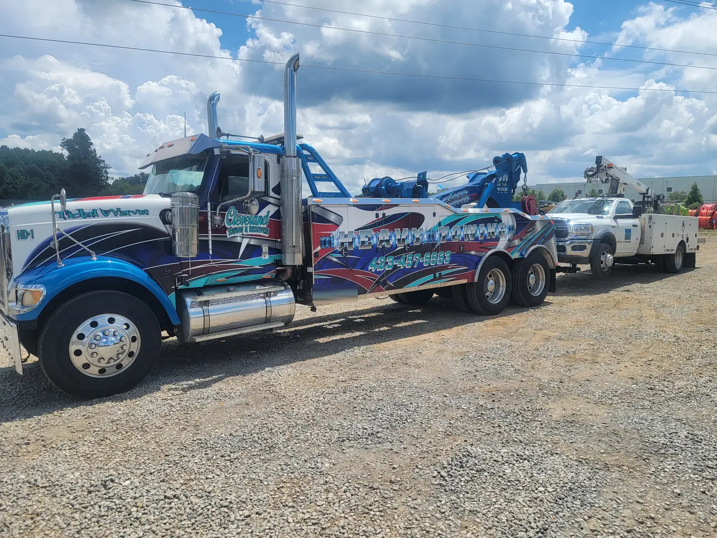The heavy wrecker hooked to a utility service truck in the yard