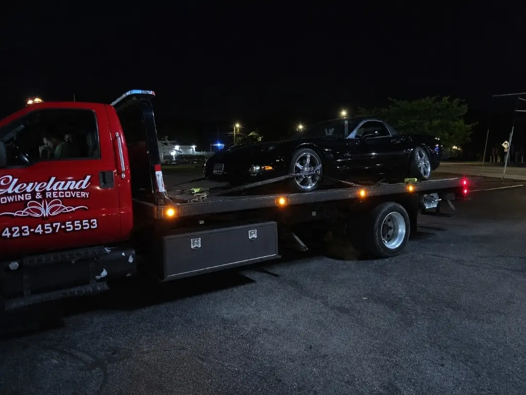A sports car loaded on the rollback on a night call