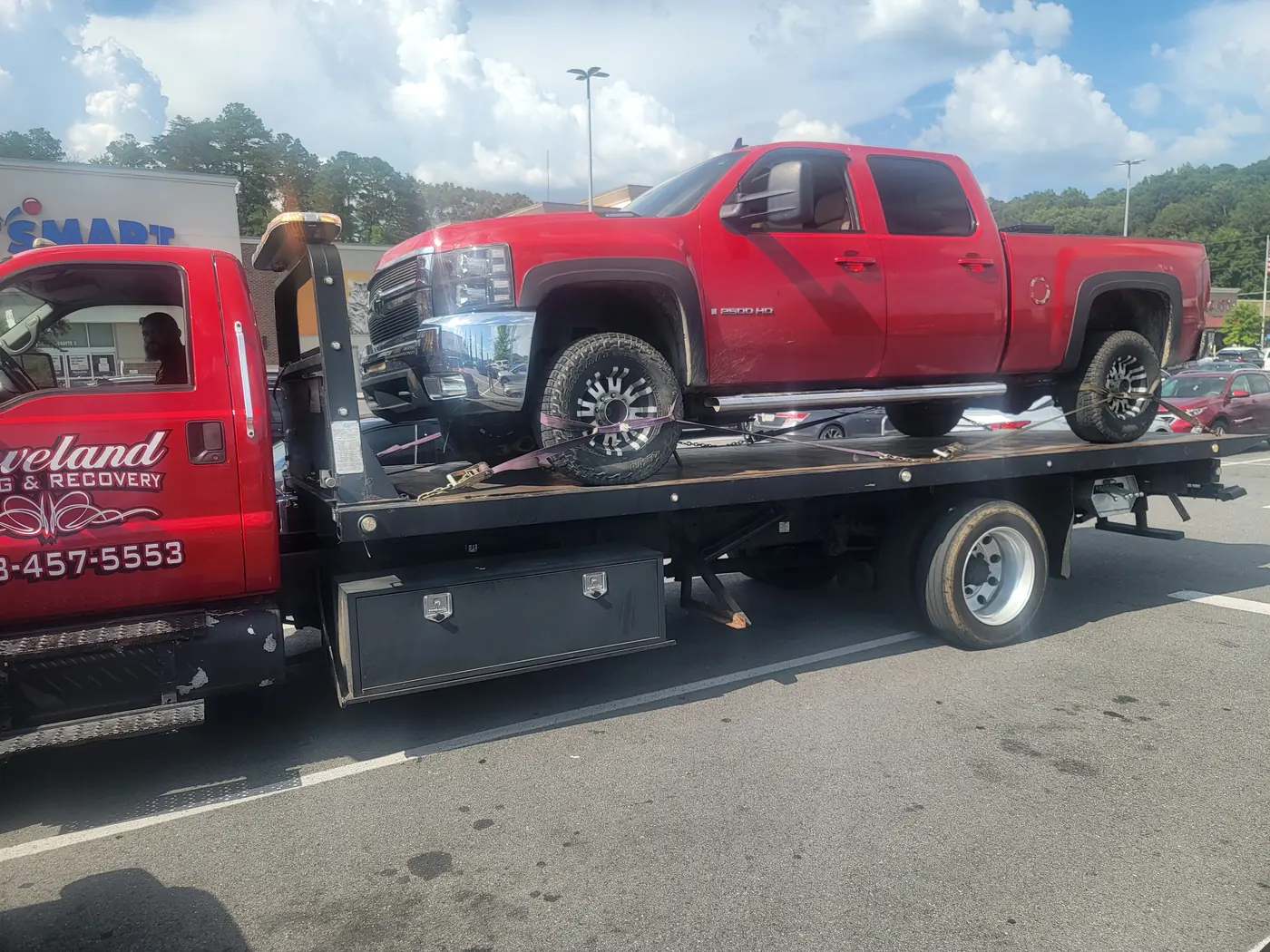 A heavy-duty pickup loaded and strapped down in a store parking lot