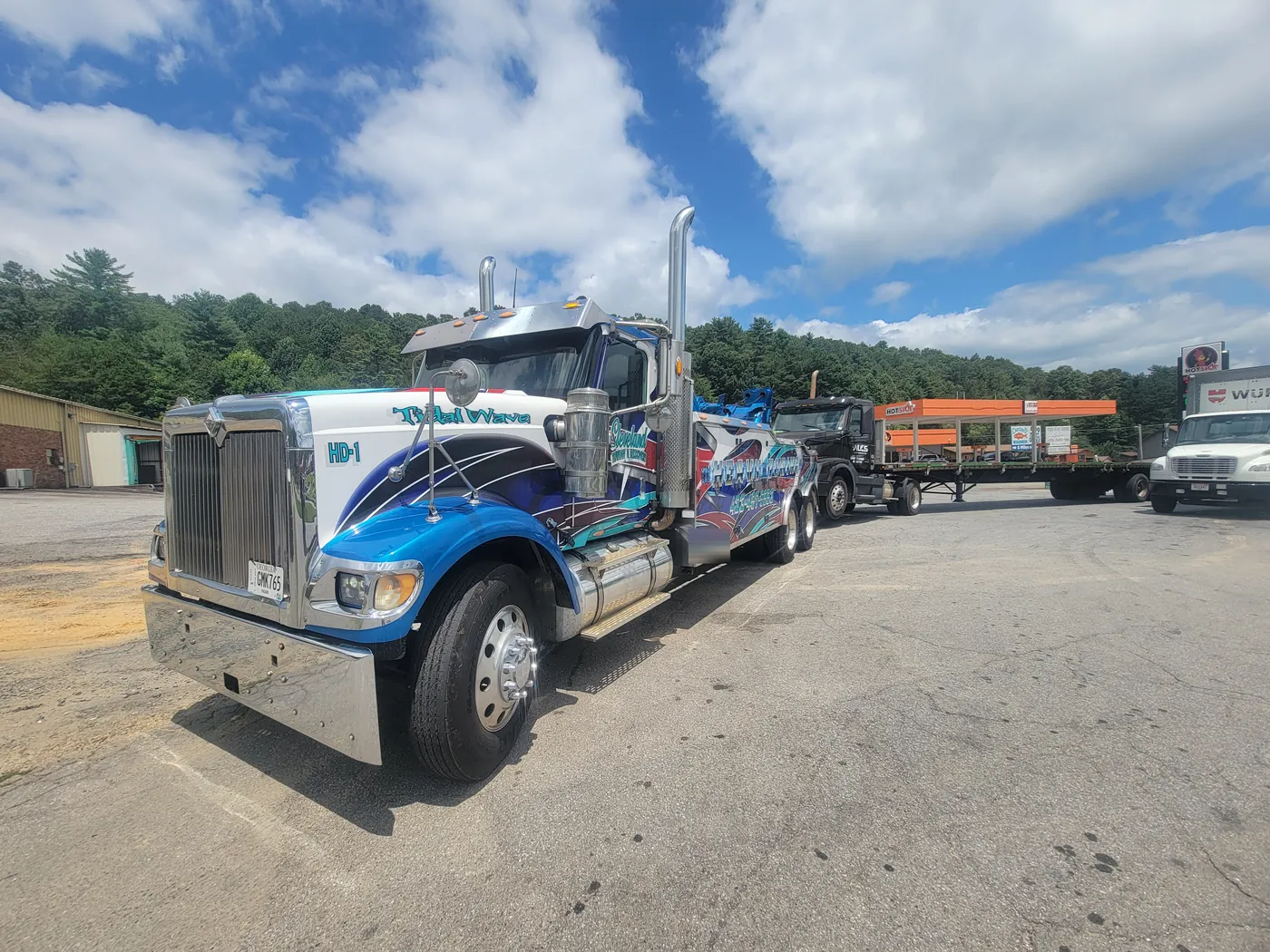 Our heavy wrecker towing a semi tractor and its flatbed trailer at a fuel stop